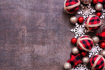 Christmas side border of red and black gingham ornaments, baubles and snowflakes. Top view on a dark brown background. Copy space.