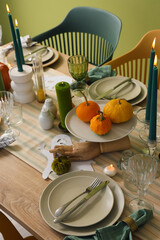 Festive table setting with burning candles and pumpkins for Halloween party, closeup