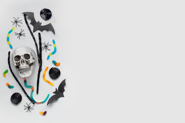 Halloween composition with skull, bats and sweet candies on grey background