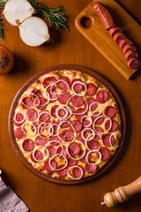 Delicious Pepperoni Pizza With Onions and Salami Slices on Wooden Table
