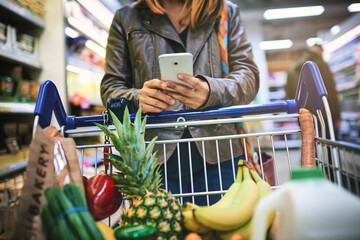 Trolley, shopping and hands of woman with phone for healthy food, website and information on items. Happy, person and customer with tech in supermarket for grocery list, app and checking ingredients