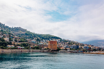 Fototapeta premium Landscape view old walls of fortress and Red tower on Mediterranean coast. View of Alanya Castle, stone ruins in harbor Alanya, Turkey. High quality photo