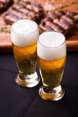 Two Refreshing Glasses of Beer with Grilled Ribs on Table