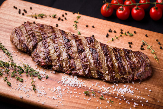 Delicious Grilled Fraldinha Steak on Wooden Board With Spices and Tomatoes
