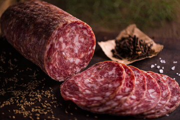 Deliciously Sliced Salami with Cloves on Rustic Wooden Board