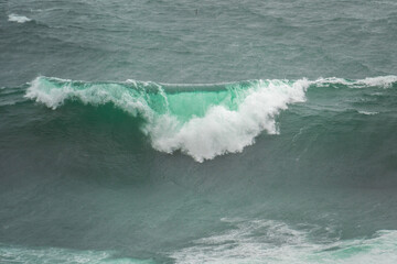 Powerful foamy waves crashing along the rugged coast of the Westfjords, Iceland, in stormy weather.