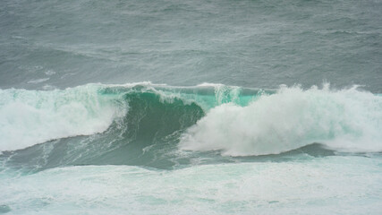 Powerful foamy waves crashing along the rugged coast of the Westfjords, Iceland, in stormy weather.