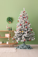 Beautiful Christmas tree with shelves near green wall