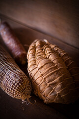 Traditional Cured Meats Wrapped in Netting on Wooden Table