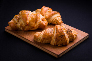 Freshly Baked Croissants on Wooden Board Against Dark Background