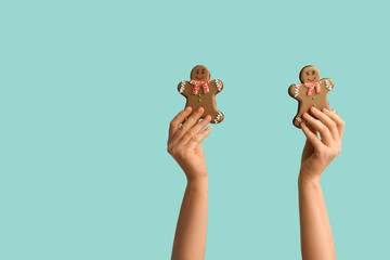 Female hands with Christmas sweet gingerbread cookies on blue background