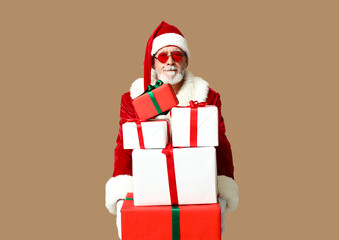 Santa Claus in sunglasses with gift boxes on brown background