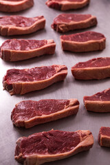 Raw Beef Steaks Neatly Arranged on Stainless Steel Surface