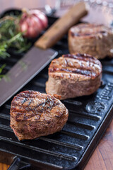 Juicy Grilled Steaks on Cast Iron Grill with Knife and Herbs