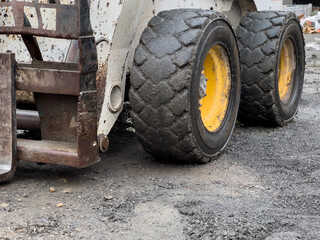 A bobcat tractor equipped with heavy tires is actively maneuvering through uneven ground at a construction site, showcasing its power and utility