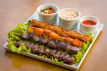 Delicious Grilled Skewers Plated With Appetizing Dips and Vegetables