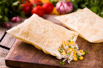 Delicious Brazilian Pastel with Chicken and Corn Filling on Wooden Board
