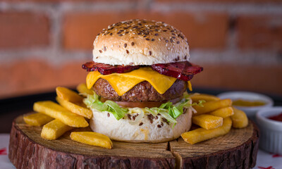 Juicy Cheeseburger with Bacon and Fries on Wooden Board