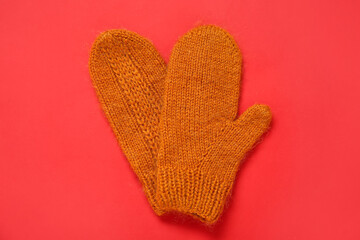Warm knitted mittens on red background