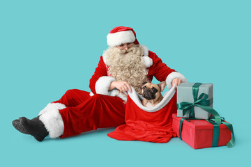 Santa Claus with Christmas gifts and French bulldog in bag on blue background