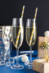 Glasses of champagne and Christmas gifts on dark background, closeup