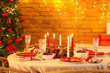 Dining table with Christmas setting and burning candles in room