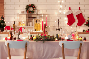 Festive table setting with Christmas decorations and glowing lights in kitchen at evening