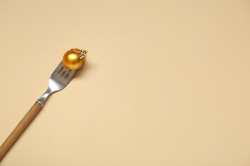 Fork with Christmas ball on beige background
