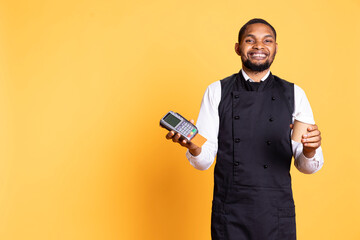 Professional friendly waiter showing the pos terminal with a credit card, symbolizing electronic payments for a meal. Restaurant employee works in a service oriented industry.