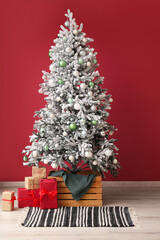 Beautiful Christmas tree and presents near color wall