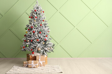 Decorated fir tree and Christmas gifts near color wall