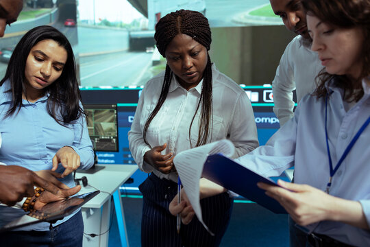 Diverse team of employees looking at cargo shipment logistics in monitoring room, tracking parcels to avoid delivery delays. Operators group following the trucks via satellite navigation.