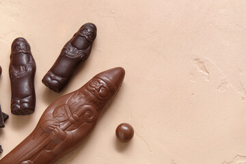 Sweet chocolate Santa Clauses on color background