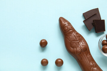 Composition with chocolate Santa Claus and candies on color background