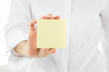 A person holds a yellow blank note paper