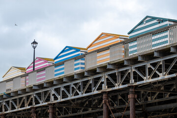 Colorful beach huts line the boardwalk along the seaside, showcasing vibrant stripes against an overcast sky
