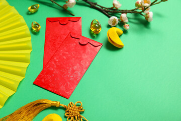 Envelopes with flower branch, fortune cookies and Chinese symbols on green background. New Year...