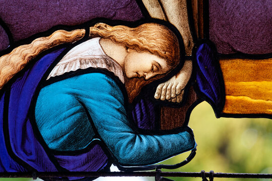 2024-10-14, Paris, FRANCE. Stained glass (19th century) of Saint Mary Magdalene at the feet of Christ on the cross.