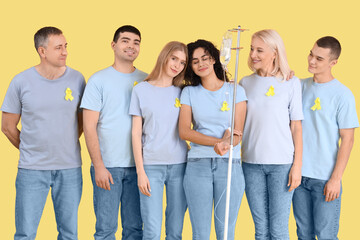 Fototapeta premium Young woman undergoing chemical therapy course and people with yellow awareness ribbons on color background. World Cancer Day
