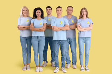 Obraz premium People with yellow awareness ribbons on color background. World Cancer Day