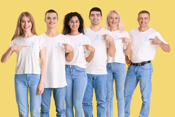Obraz premium People pointing at blue awareness ribbons on yellow background. World Cancer Day