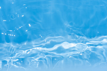 Blue water with ripples on the surface. Defocus blurred transparent blue colored clear calm water surface texture with splashes and bubbles. Water waves with shining pattern texture background.