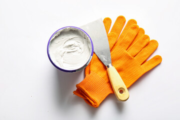 Knife, gloves and can of putty on white background