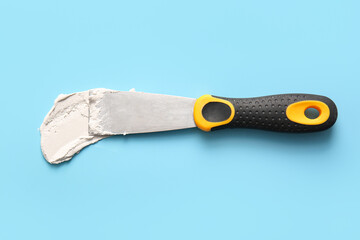 Knife with putty on blue background