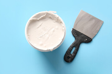 Knife and can of putty on blue background