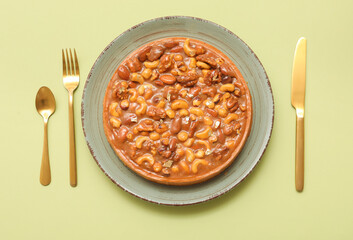 Plate of sweet tart with different nuts and caramel on green background