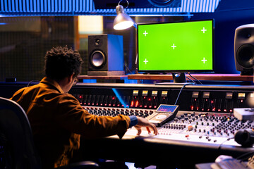 African american audio technician works with mockup layout on pc, adjusting volume levels with...