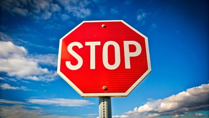 Obraz premium Red stop sign is standing against a blue sky, with white clouds passing by