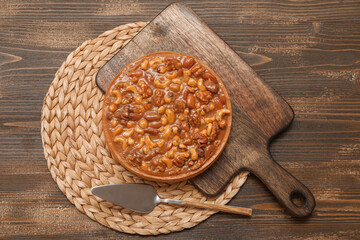 Board of sweet tart with different nuts and caramel on wooden background