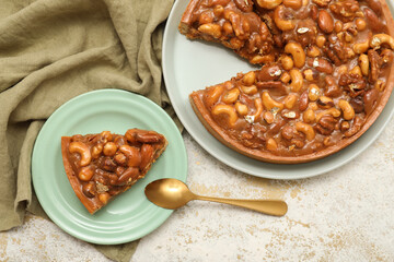 Plates of cut sweet tart with different nuts and caramel on white background